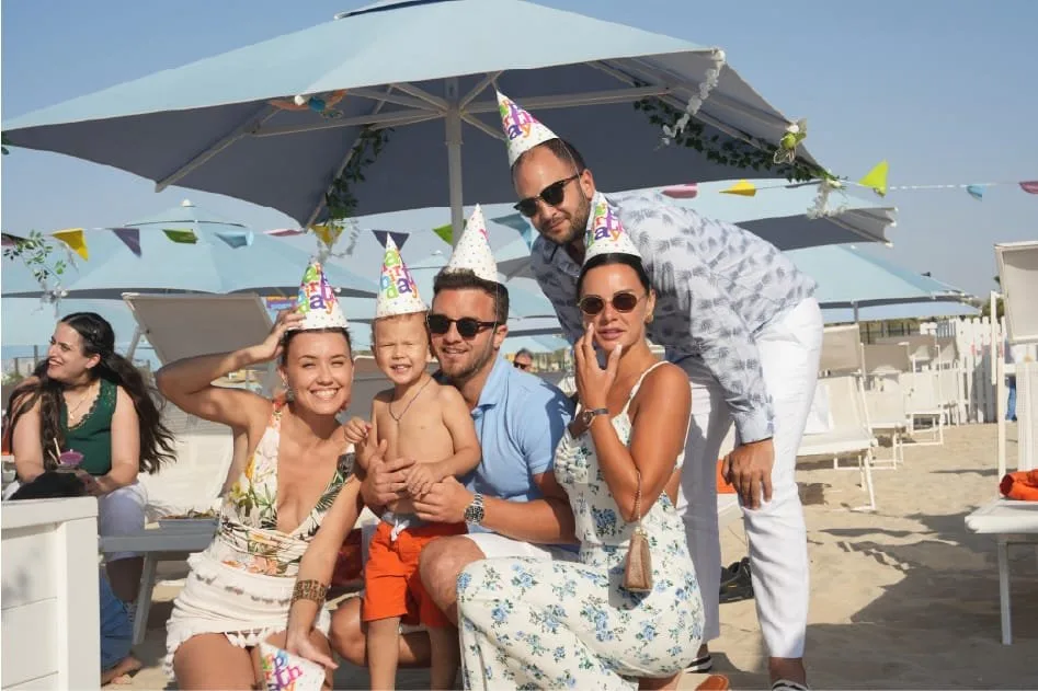 Family and friends celebrating a birthday under Sole Mio beach umbrellas