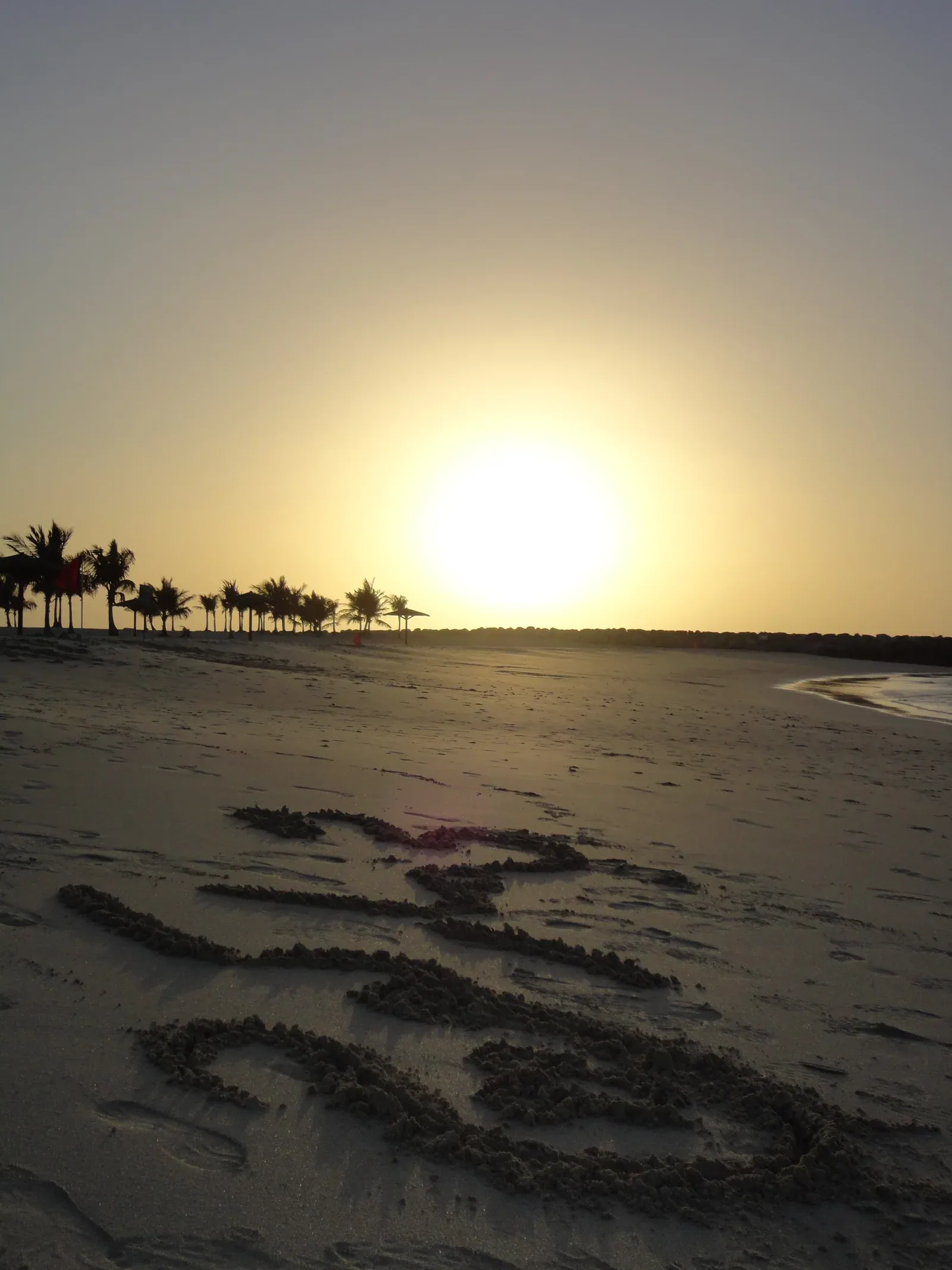 Sunset over the sand and water at Al Mamzar Beach Park