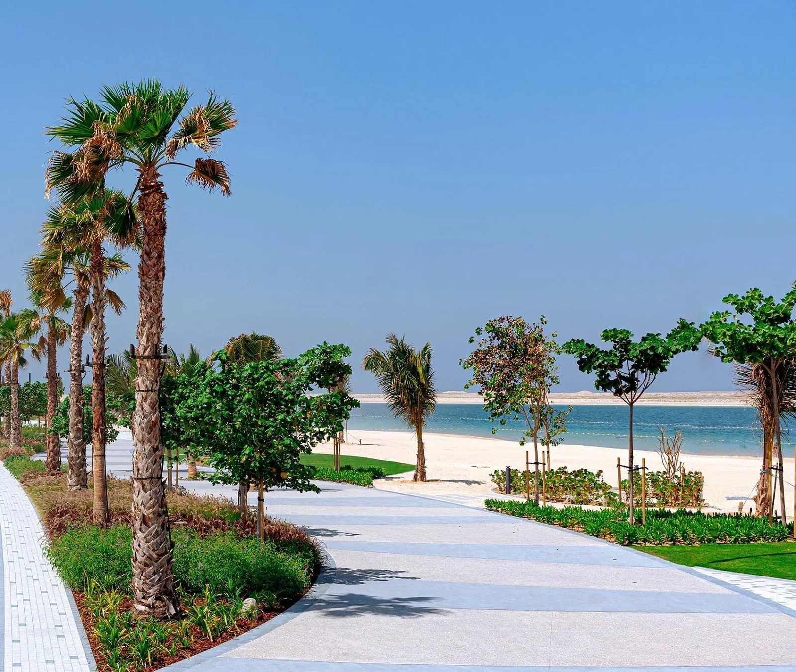 Palm-lined promenade beside the sand and sheltered water at Dubai Islands Beach