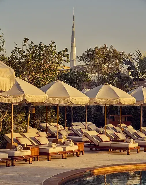 Pool edge, sunbeds and cream parasols at Gigi Rigolatto with Burj Khalifa in the background