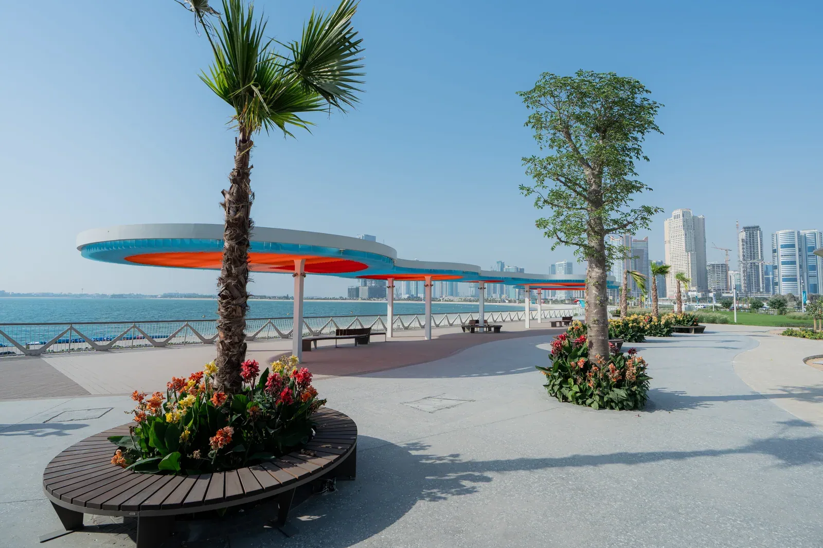 Landscaped Khor Al Mamzar waterfront promenade with shaded benches
