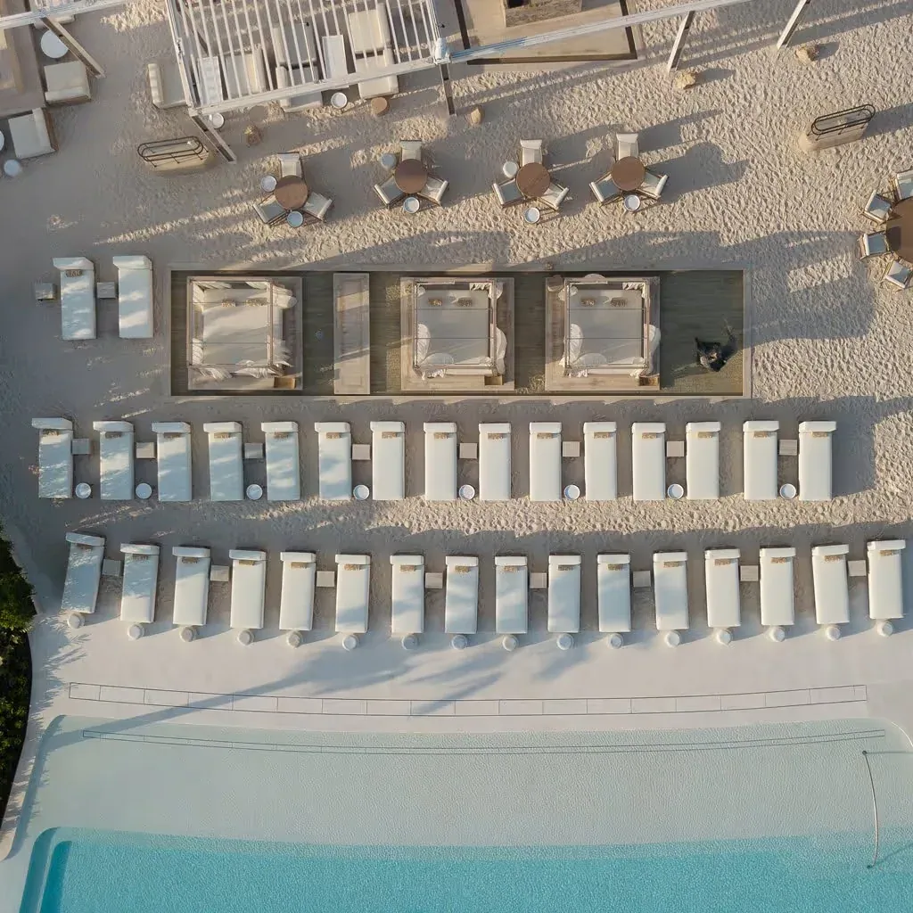 Overhead view of sunbeds, three cabanas and a pool at The Club on Palm West Beach