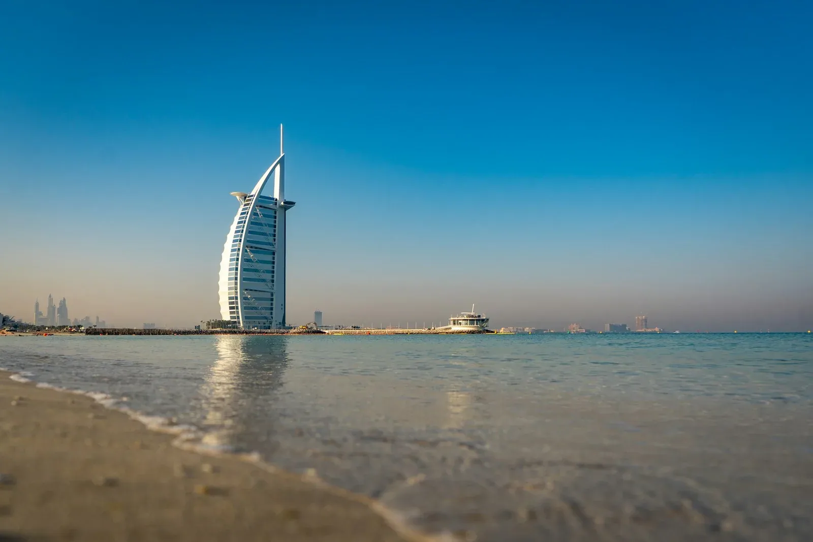 A wave reaches the Umm Suqeim shoreline with Burj Al Arab in the distance