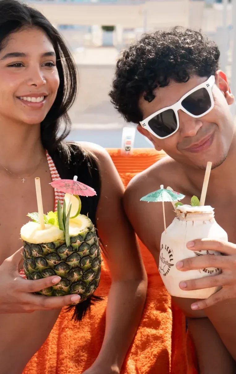 Two friends enjoying fresh drinks on orange Sole Mio towels