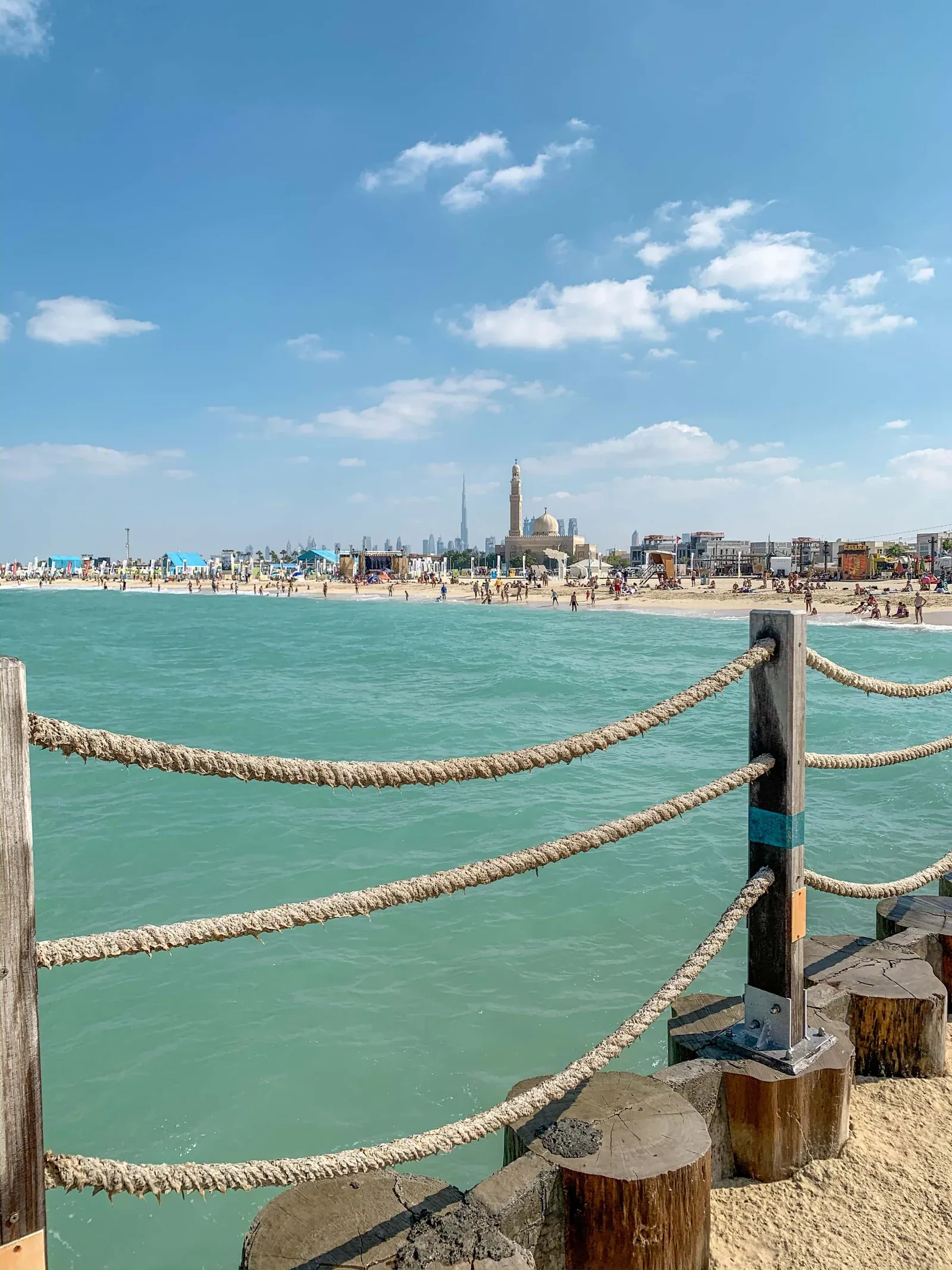 Turquoise water beside Kite Beach, with the beachfront mosque and Dubai skyline beyond