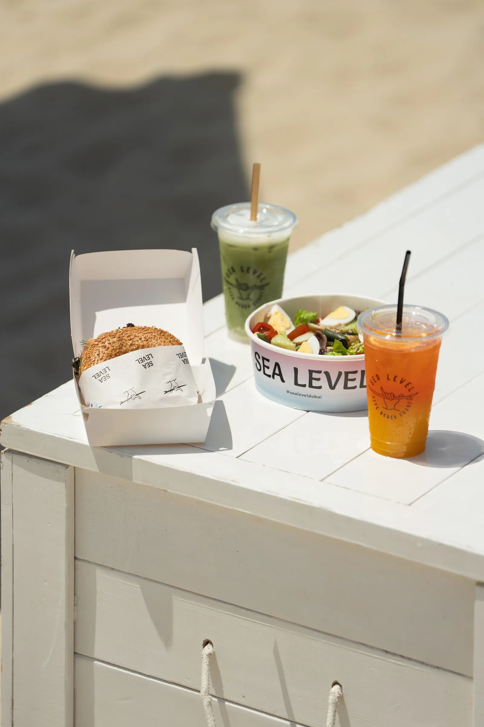 A Sea Level Café sandwich, salad and fresh drinks on a beach table