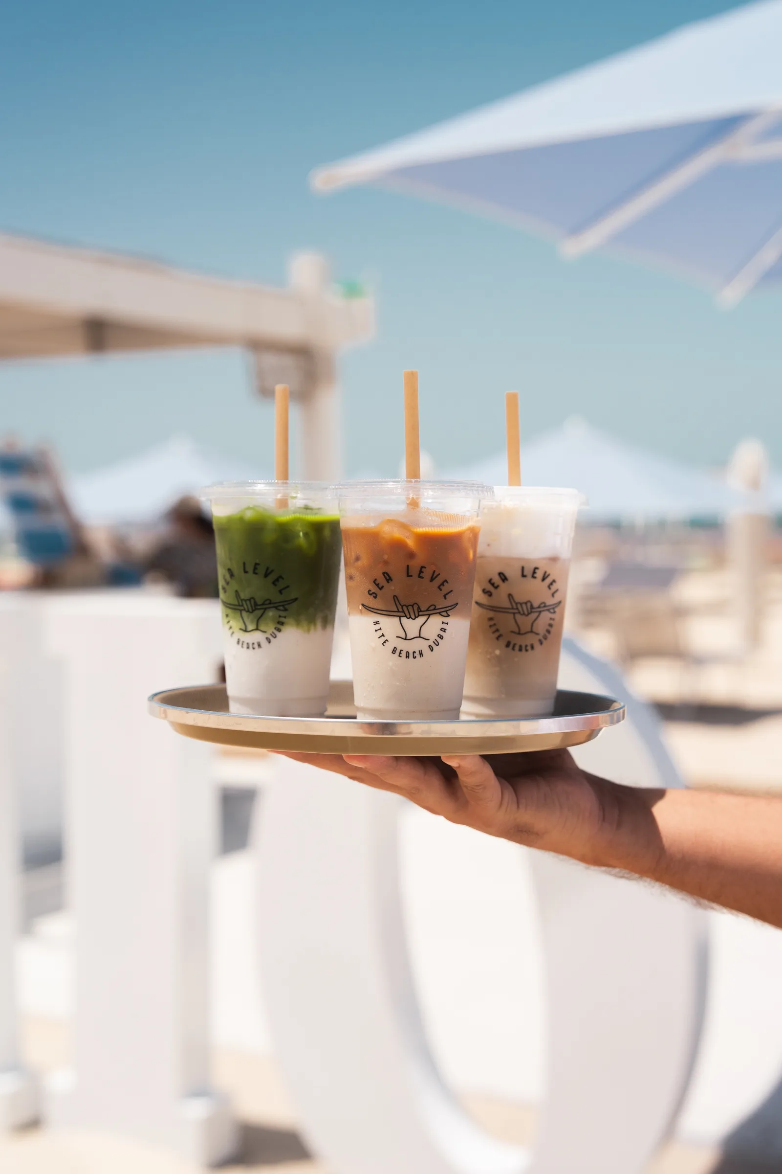 Iced matcha and coffees from Sea Level Café served on a tray beneath the blue umbrellas