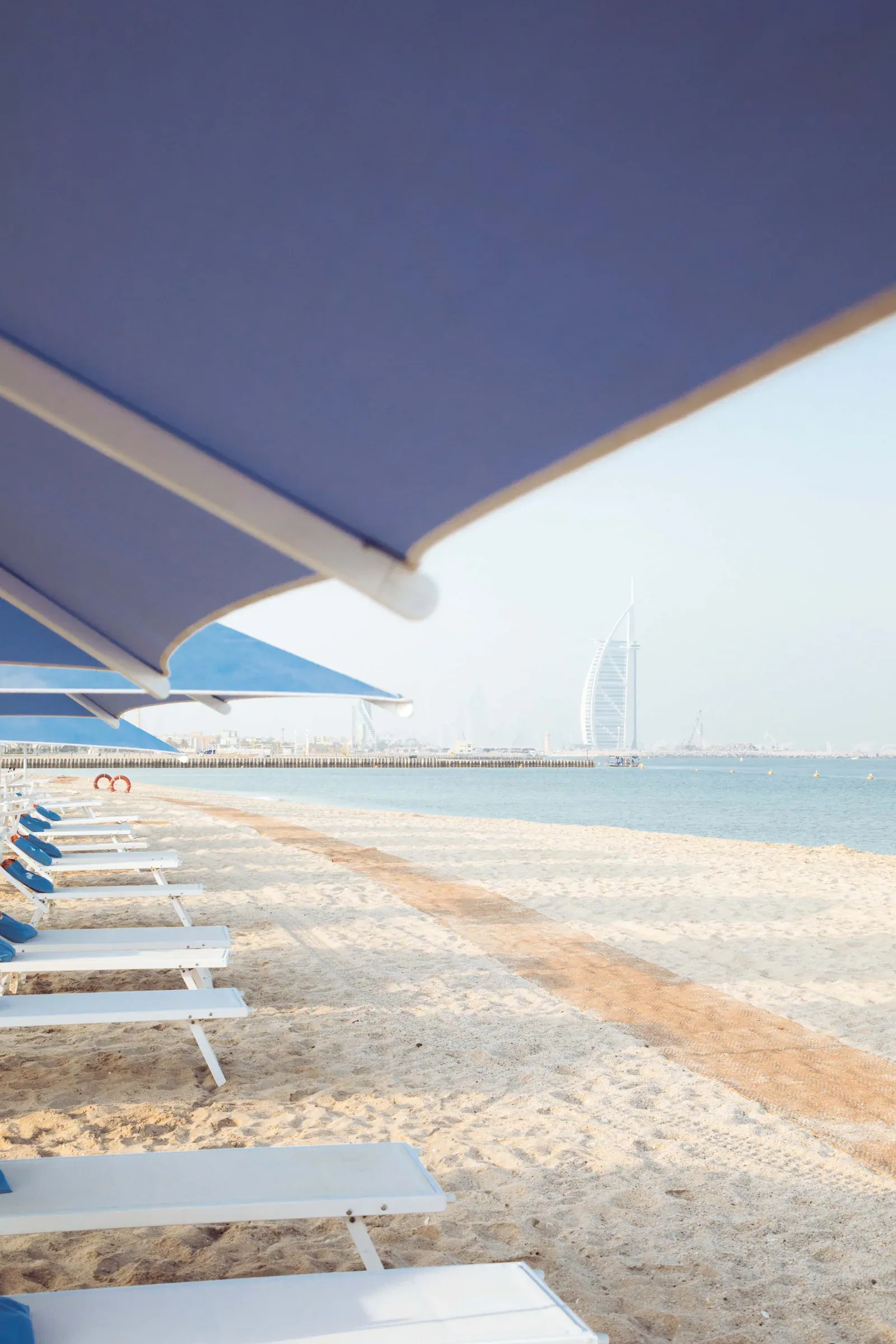Blue Sole Mio parasols and white sunbeds facing the sea and Burj Al Arab at Kite Beach