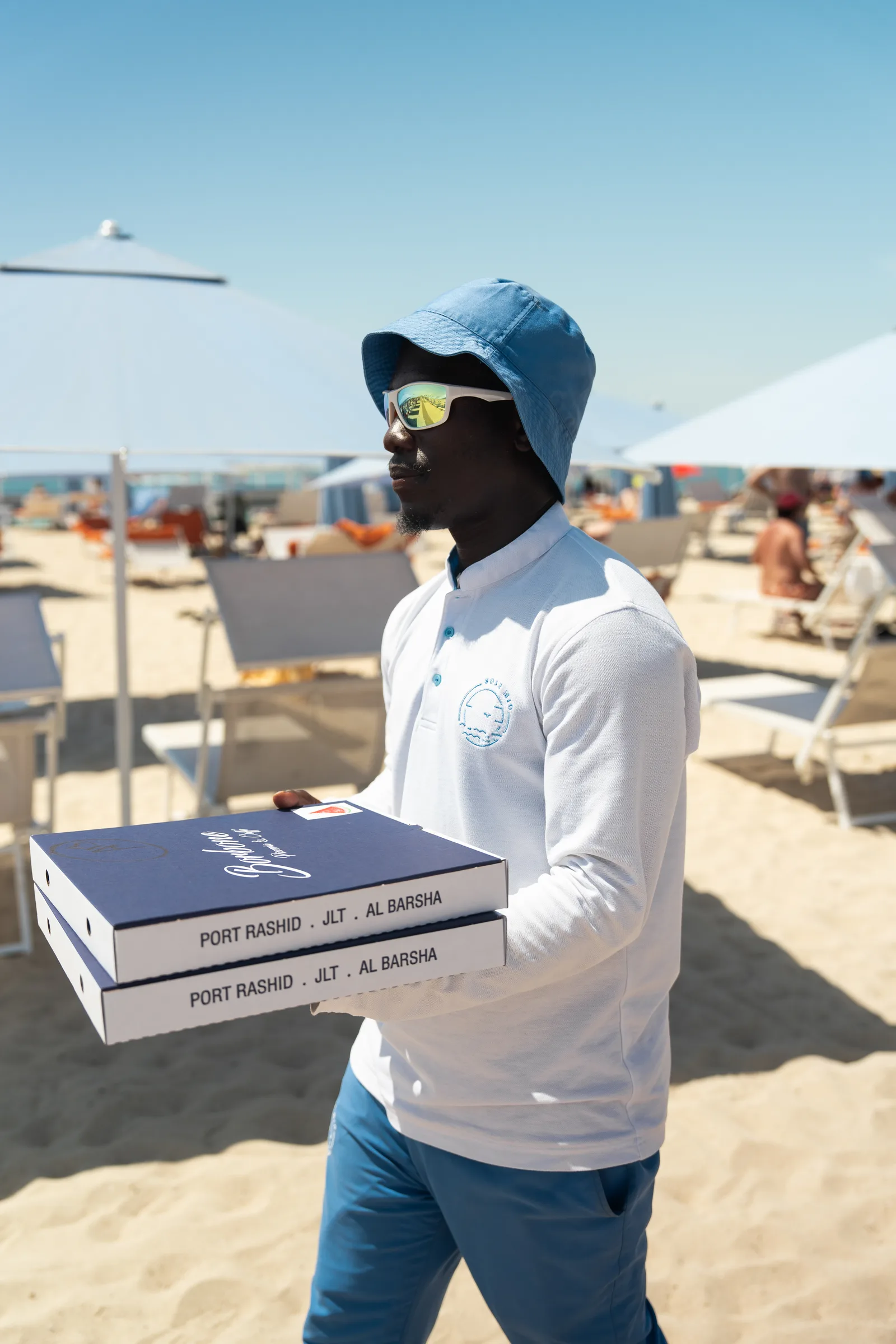 A Sole Mio team member carrying Caffè Borbone pizza boxes to the beach